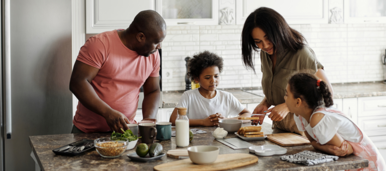 parents with two daughters making a meal over a kitchen island