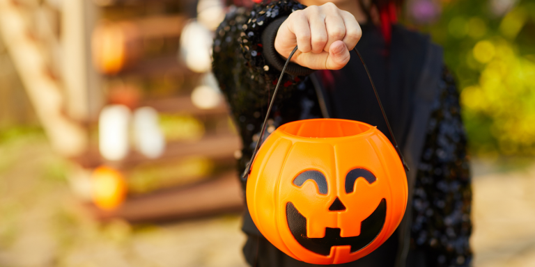 a child is holding a Jack-O-Lantern Trick-or-Treat candy bucket