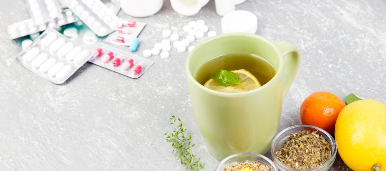 a cup of tea with a lemon slice in it next to pills