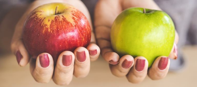 a woman holding a red apple in her left hand and a green apple in her right hand