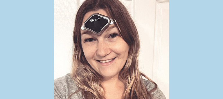 a smiling woman wearing a CEFALY device on her forehead