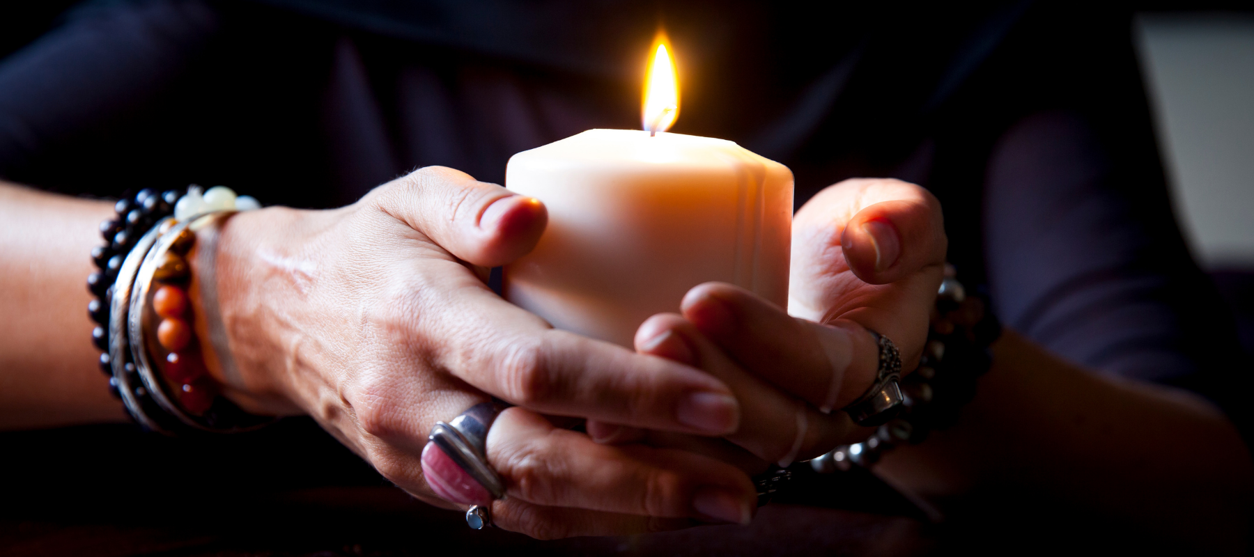 a woman holds a lit candle in her hands