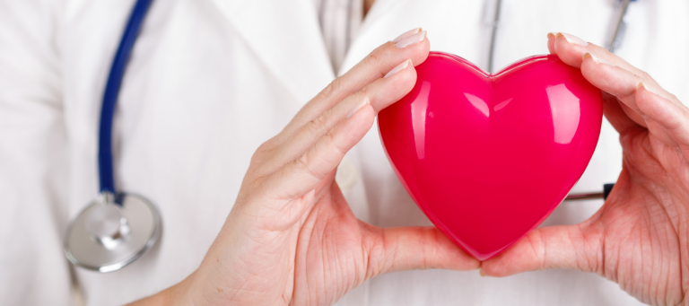 a doctor is holding a red heart in her hands