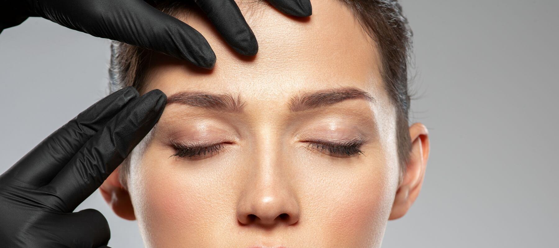 a woman's face is being examined by a person wearing black gloves