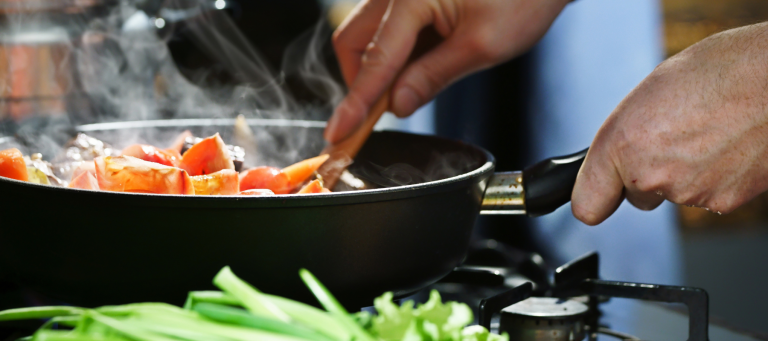 a person is stirring vegetables in a pan on the stove with a wooden spoon