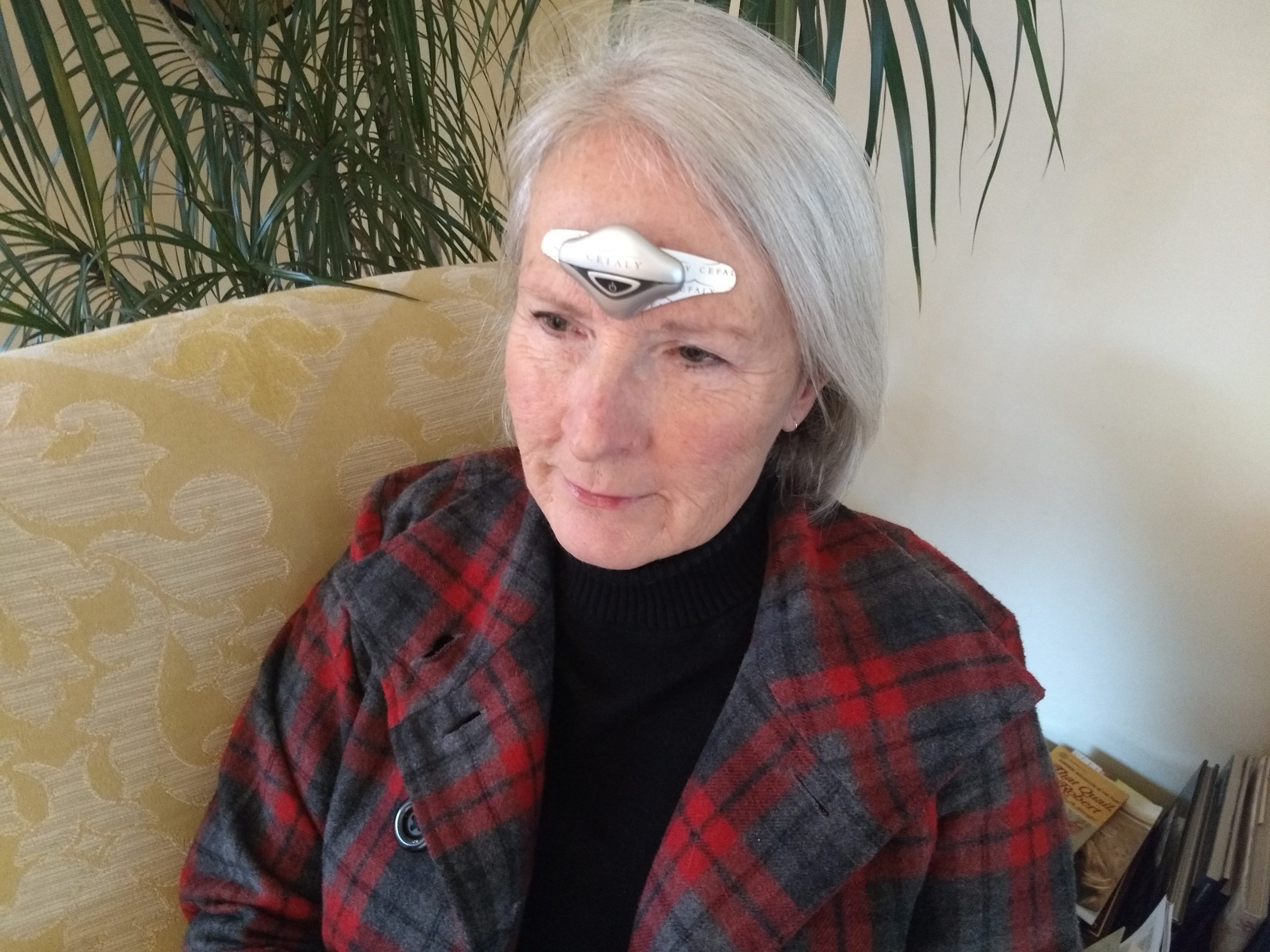 an elderly woman with a CEFALY device on her forehead