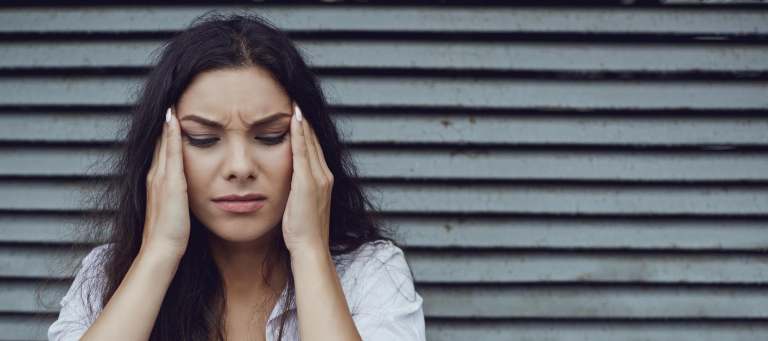 a woman in pain is holding her head with her eyes closed