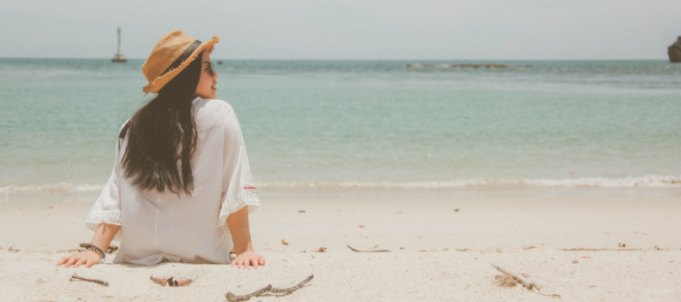 woman sitting on sand in front of ocean