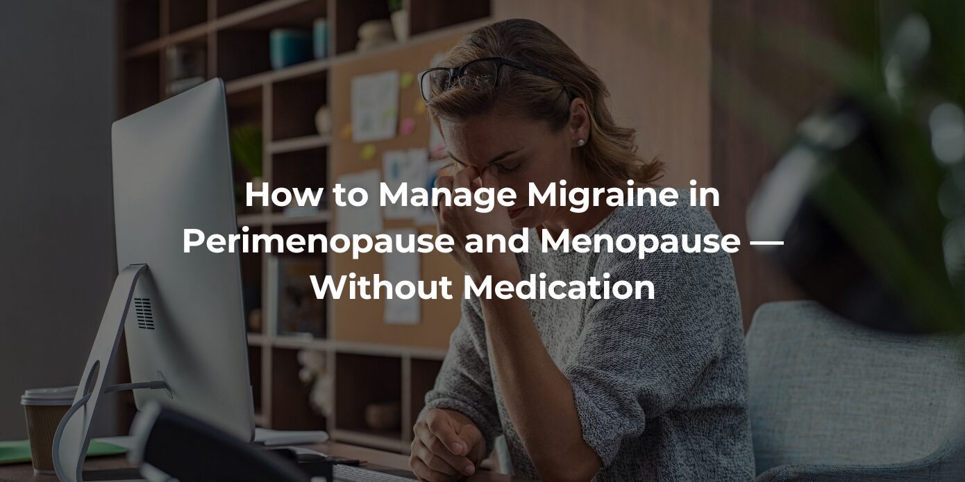 A woman in her 40s holds her head while working at a desk